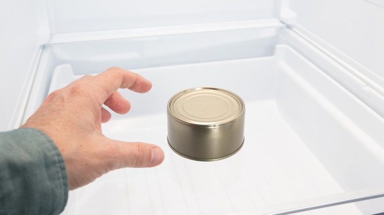 Person removing metal can from refrigerator
