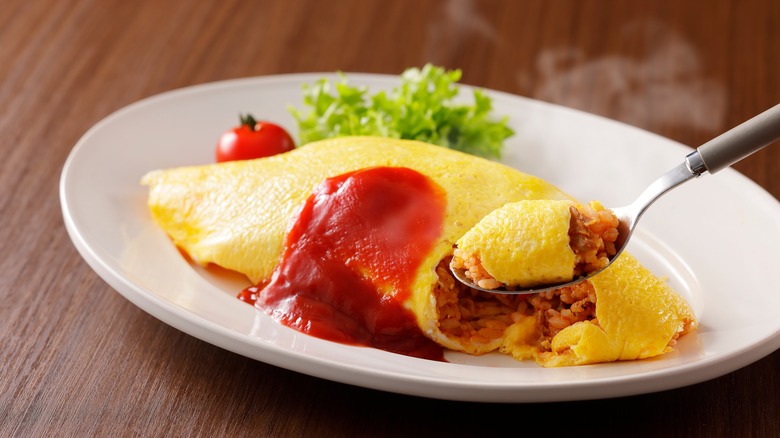 Japanese omu rice topped with ketchup and garnished with lettuce and tomato