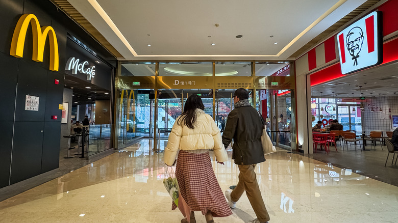Patrons walking in a mall in Chongqing, between two food giants McDonalds and KFC