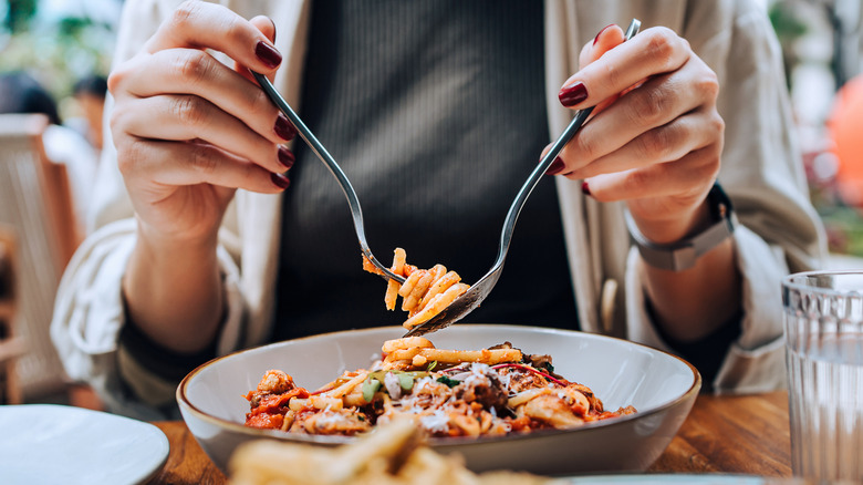 Person eating pasta outdoors