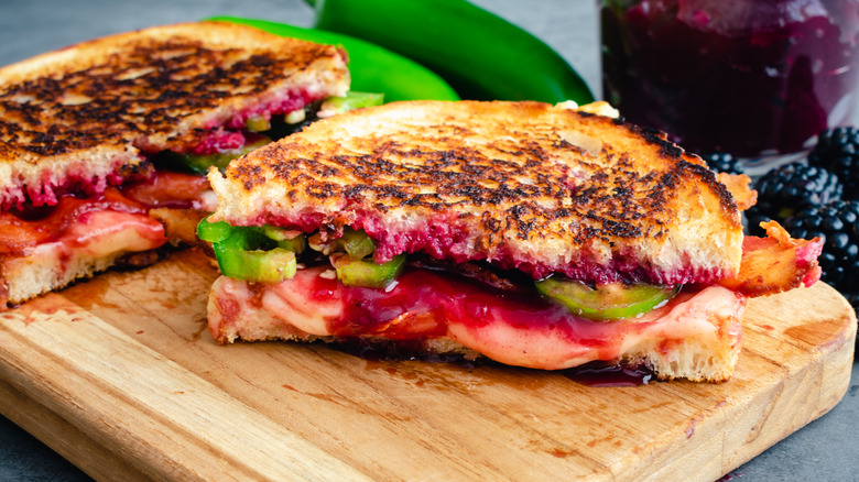 A fancy grilled cheese with jam, sliced to serve on a wooden platter