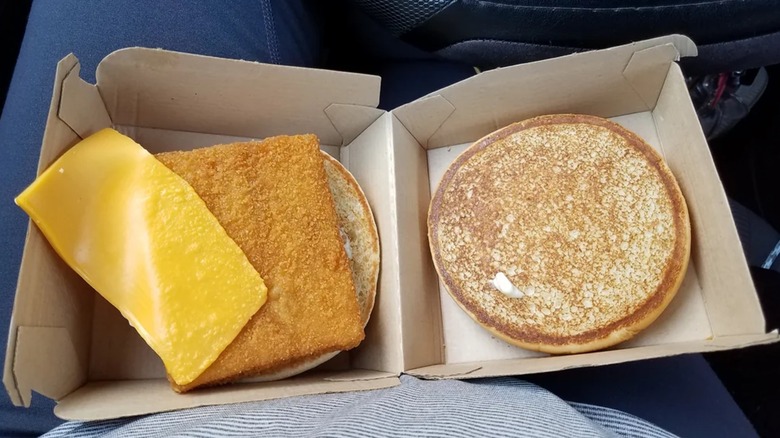 A dismantled Filet-O-Fish from McDonald's with a lopsided piece of cheese on top of the fish