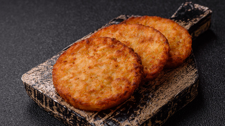 Round hash browns on a wooden paddle.