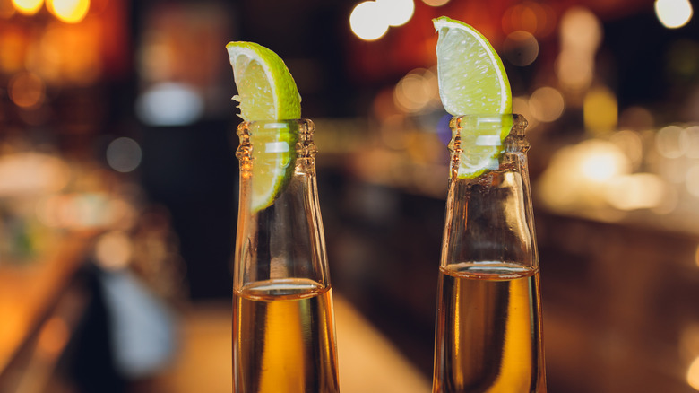 closeup two beer bottles with lime wedges stuck in the top