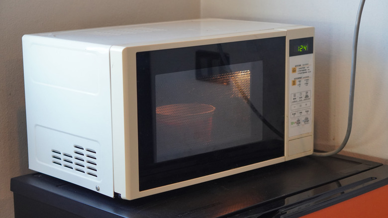 A white microwave heats a bowl of food
