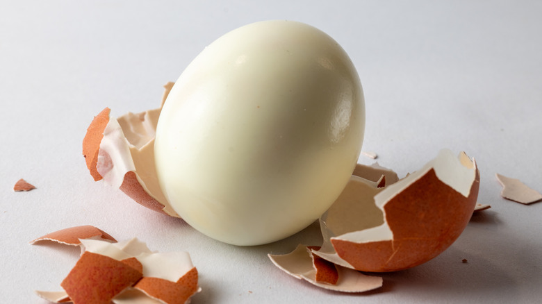 Peeled hard-boiled egg on a broken shell on a table.