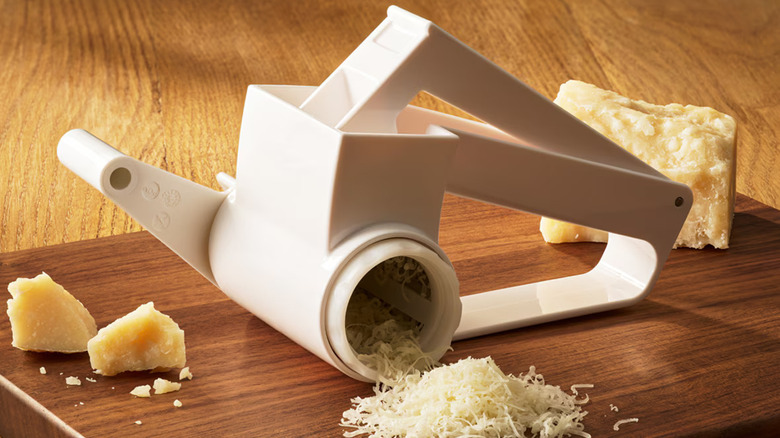 Olive Garden's Cheese Grater rests on a wooden block near chunks of romano cheese