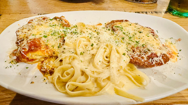 An Olive Garden entree with pasta and chicken cutlets topped with parmesan cheese