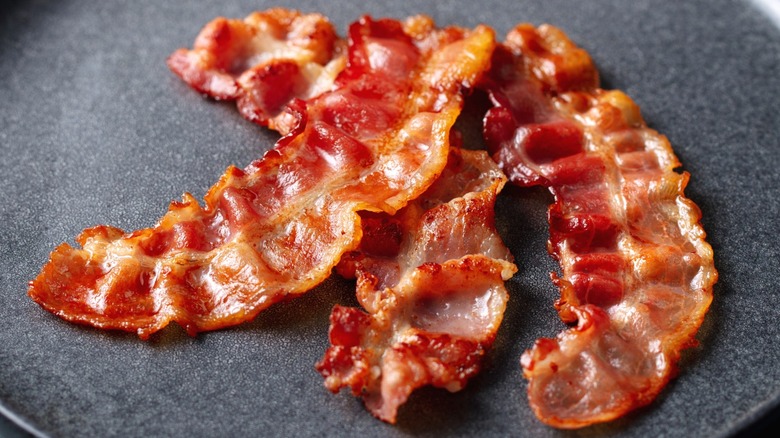 Crispy bacon strips on a black plate.