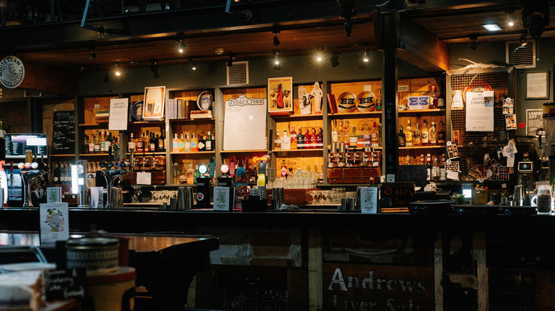 The bar at a British pub with beer taps and shelves with liquor bottles