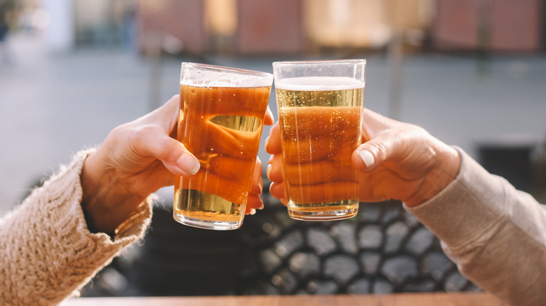 Two pint glasses full of beer raised in a toast