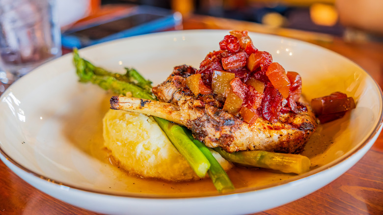 Grilled pork chop, chutney, mashed potatoes, and asparagus at a restaurant