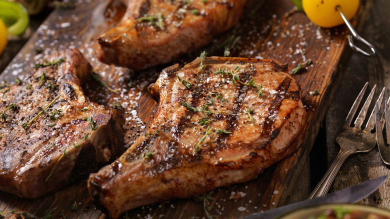 Crispy pork chops with salt and herbs on them on a wooden board