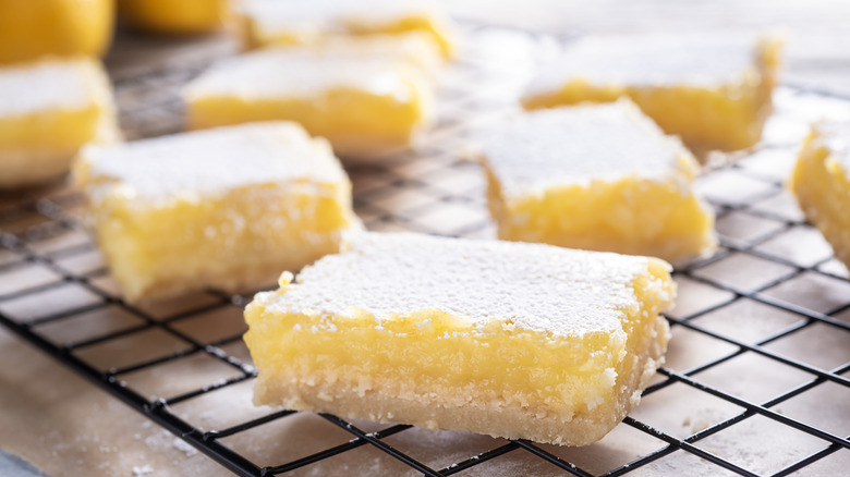 Homemade lemon squares topped with powdered sugar on a cooling rack