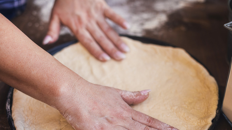 Woman preparing pizza dough to get baked