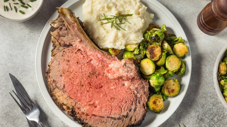 Prime rib served with mashed potatoes and Brussels sprouts.