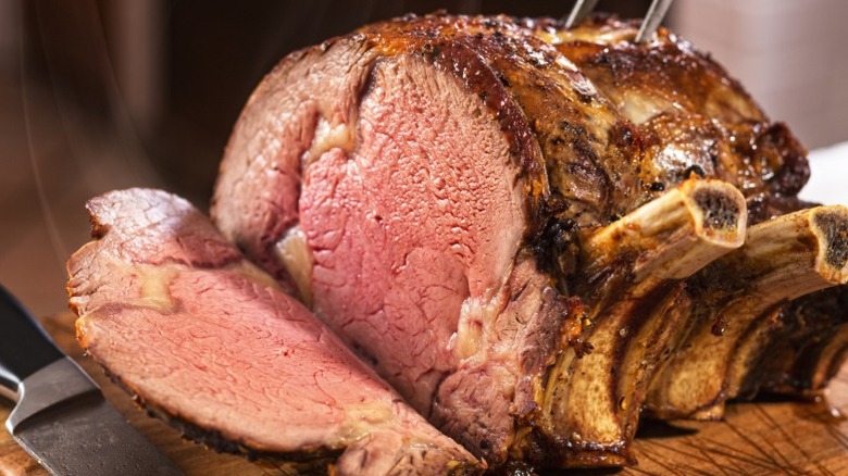 A prime rib on a wooden cutting board.