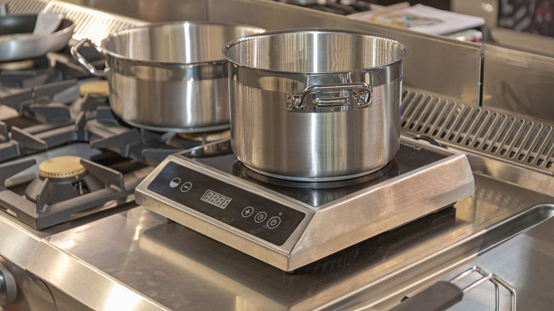 A stainless steel pot on a professional induction cooktop
