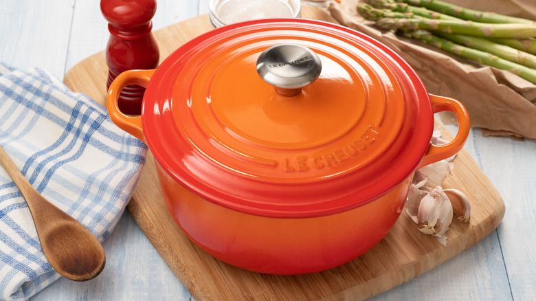 Orange Le Creuset Dutch oven with vegetables and seasonings