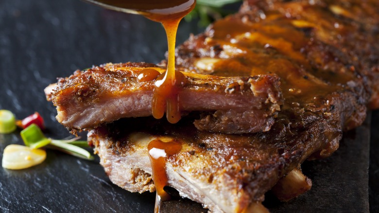 Barbecue sauce being spooned over ribs