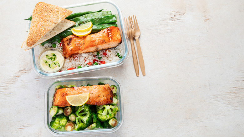 Top view of food storage containers with cooked salmon, rice, and vegetables