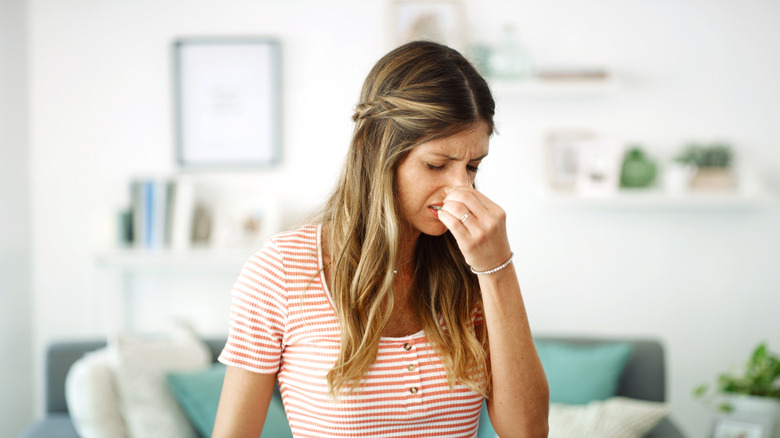 Bad smell, woman pinching her nose