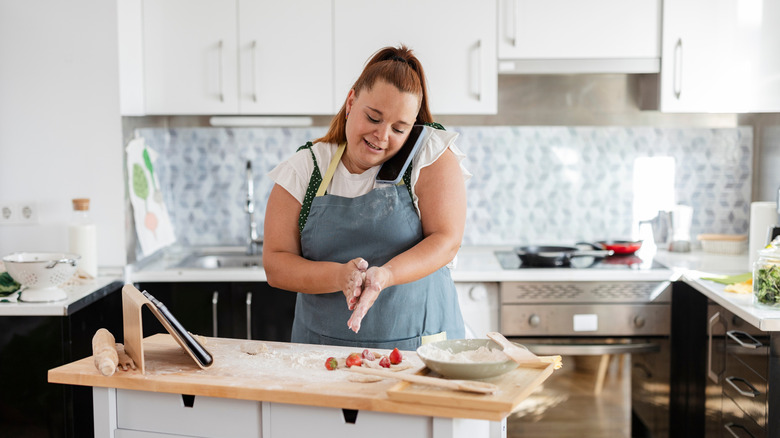 Woman cooking in home kitchen while talking on the phone