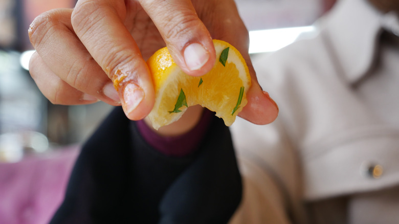 Hands squeezing lemon on to dish
