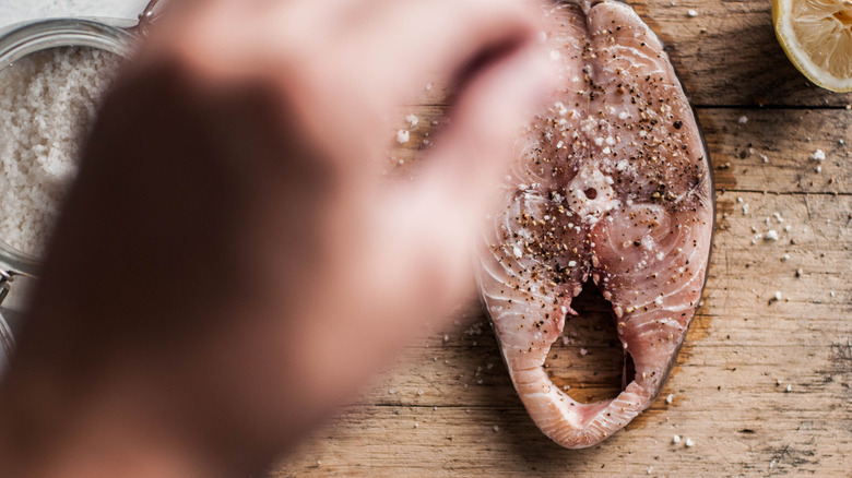 Close up of hand salting fish