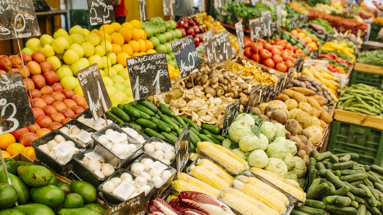 An outdoor produce market with bins of various fresh fruits and vegetables