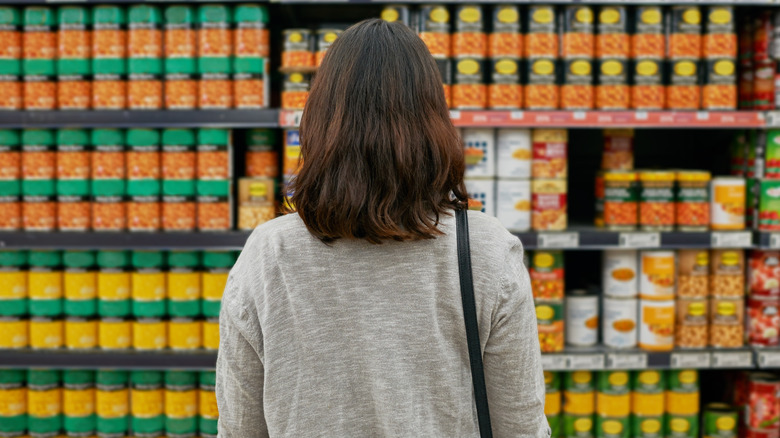 Person considering buying canned products at the grocery store