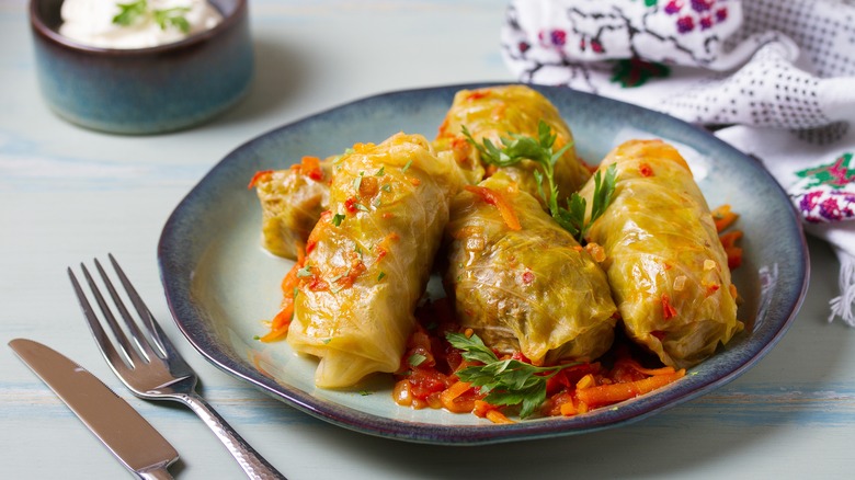 stuffed cabbage leaves on plate with carrot and parsley