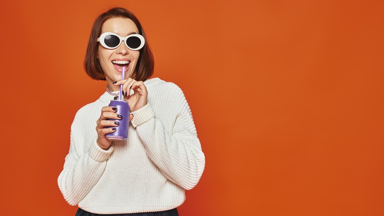 A woman drinking unmarked soda from a straw
