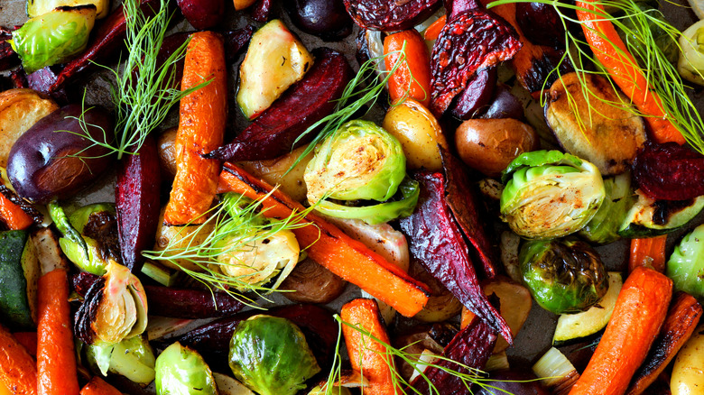 A tray of roasted vegetables pictured closeup with bright colors of green, orange, and purple.