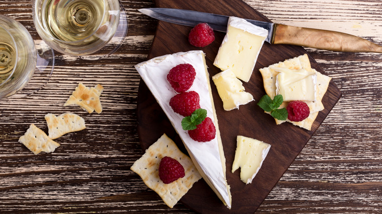 Cheese platter on rustic wooden board, Brie cheese with rasperries on top