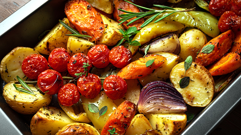 A pan of oven-roasted vegetables with herbs and garnishes on top