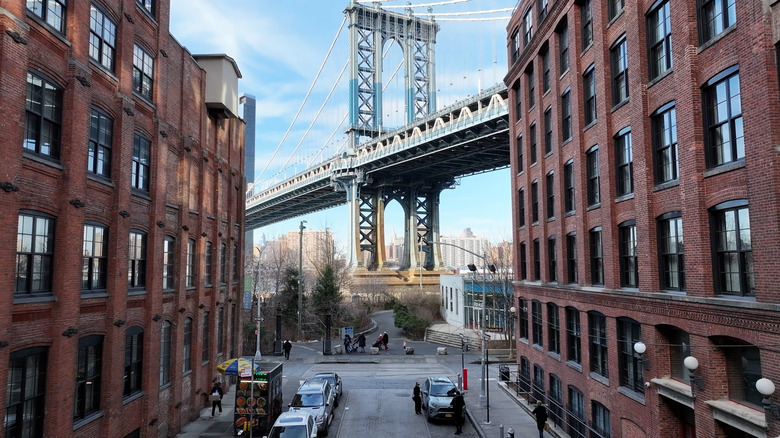 The Brooklyn Bridge towers over brick buildings in Brooklyn, New York