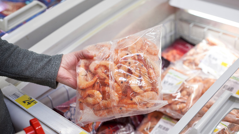 Person holding bag of frozen shrimp at supermarket