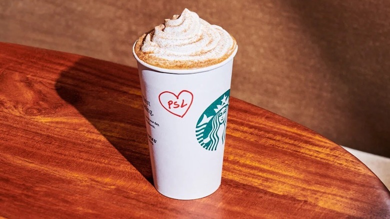 A Starbucks Pumpkin Spice Latte on a wooden cafe table