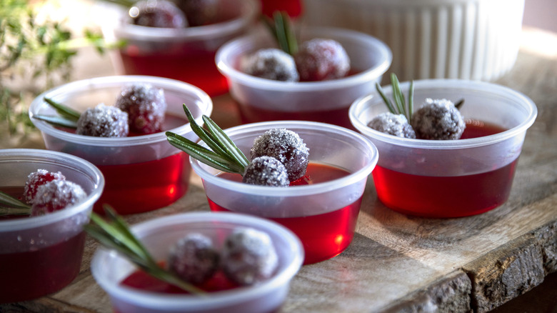 Festive frosted cranberry Jell-O shots in small plastic cups