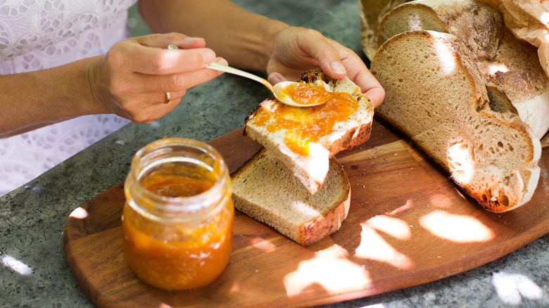 A woman spreading jam on bread