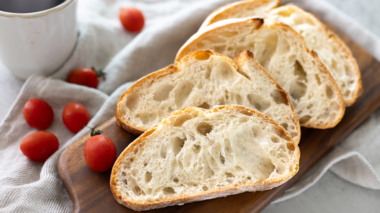 sliced ciabatta bread on wooden board and crumpled napkin