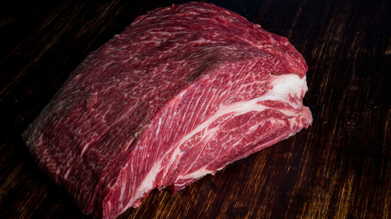 A piece of dry-aged chuck roast on a dark wooden counter