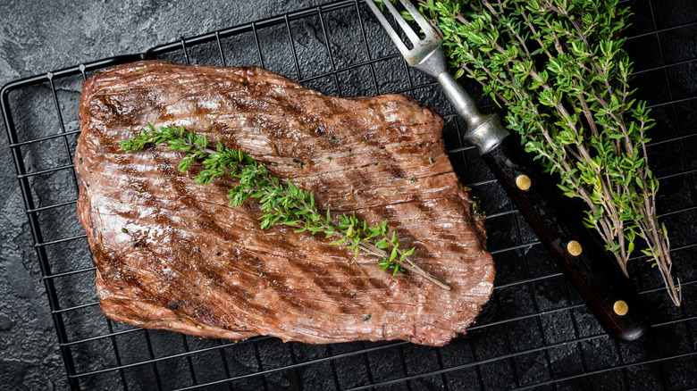 grilled merlot steak resting on wire rack with thyme and fork