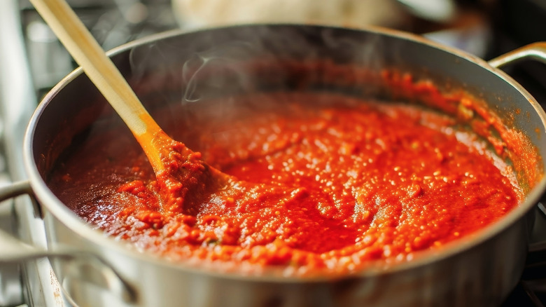 Tomato sauce cooking in a pot with a wooden spoon