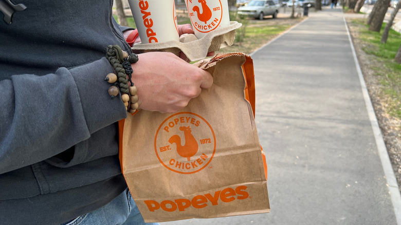 person carrying takeout from Popeyes