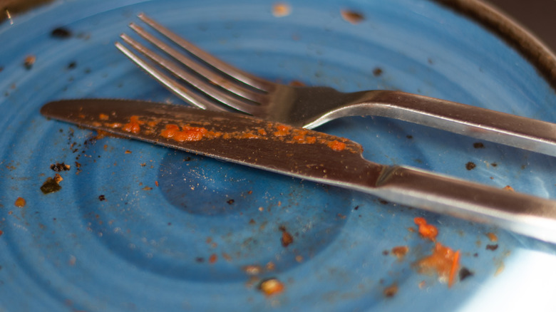 A knife and fork on a blue plate after lunch