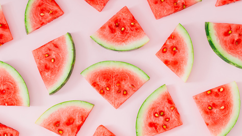 An array of watermelon slices on a light pink background.