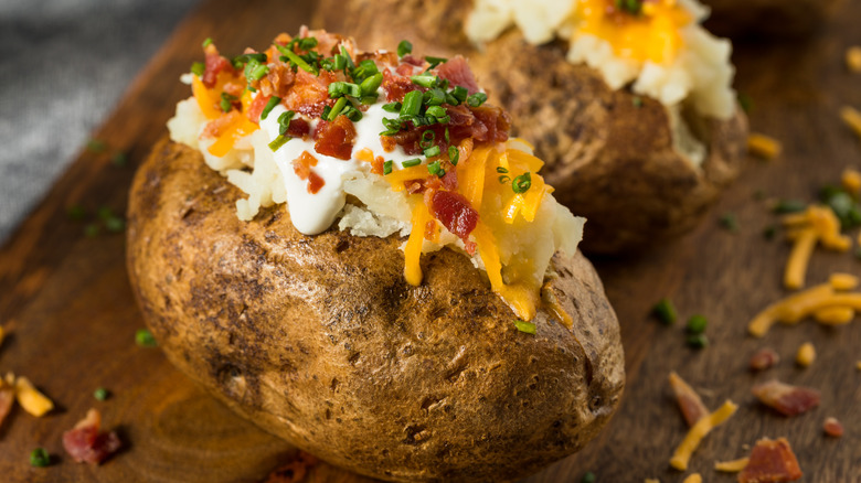 A baked potato topped with sour cream, bacon, cheese, and chives