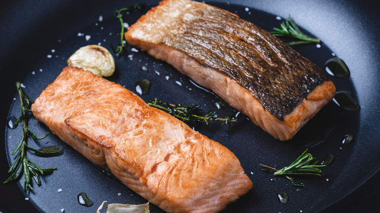Grilled salmon filets in a frying pan with garlic and herbs